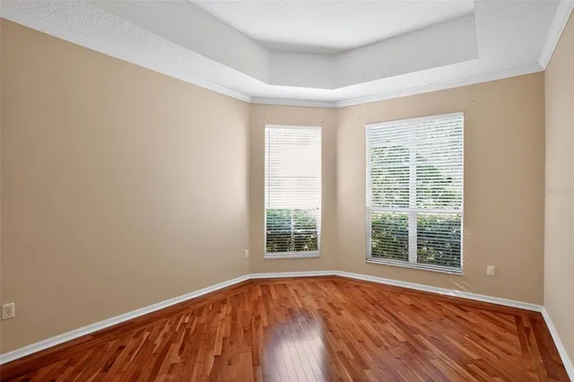 a view of an empty room with window and wooden floor