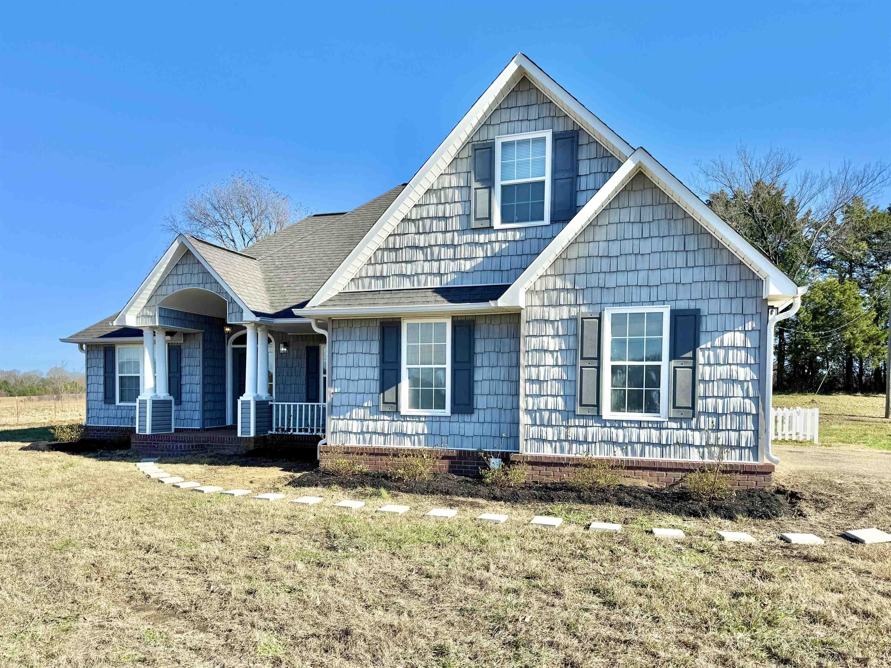 View of front of property featuring a front lawn and a shingled roof