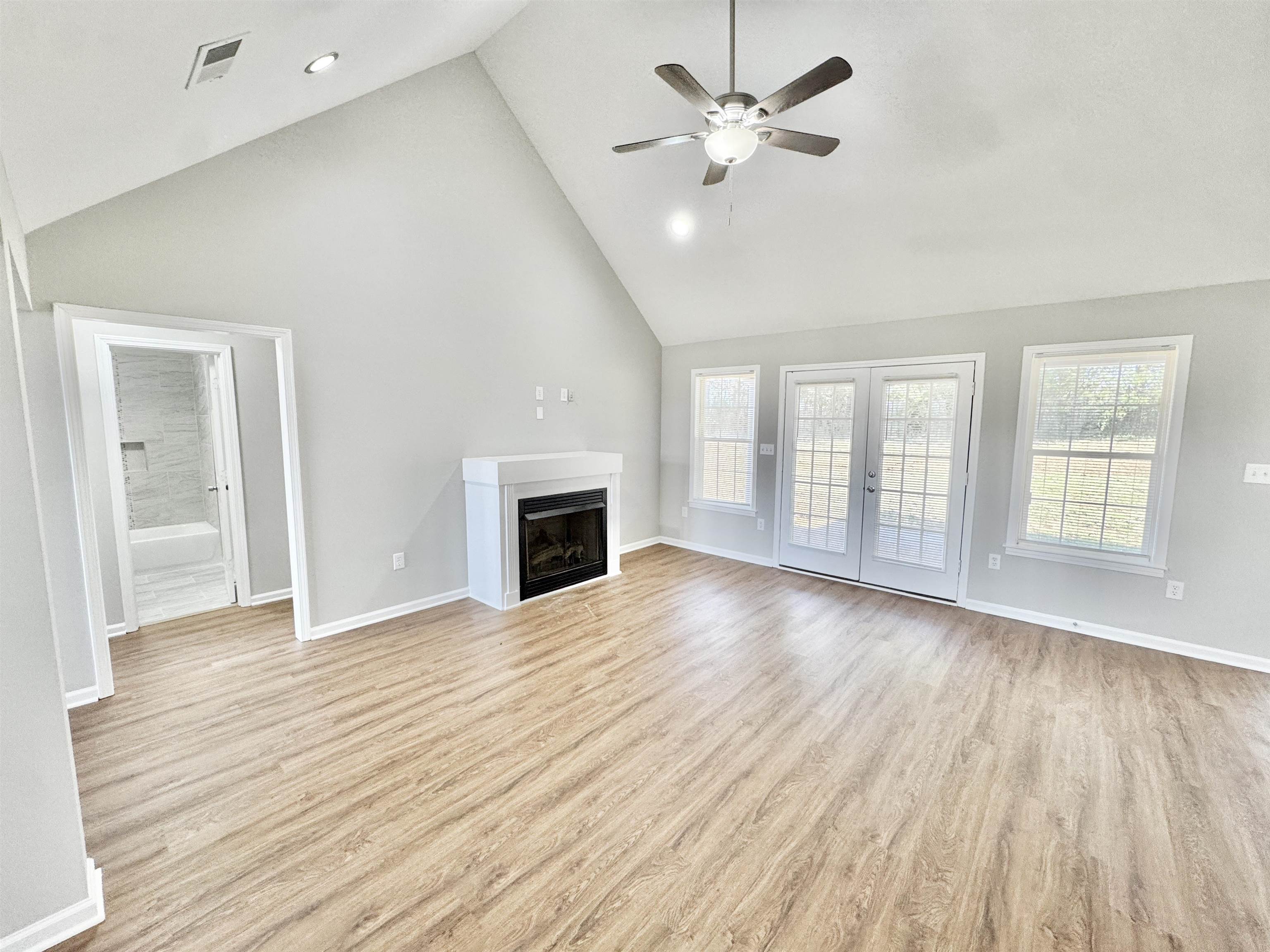 788 Bruce Road Whiteville, TN 38075 - Photo 11 of 39 Unfurnished living room with high vaulted ceiling, a fireplace, french doors, a ceiling fan, and light wood-style floors