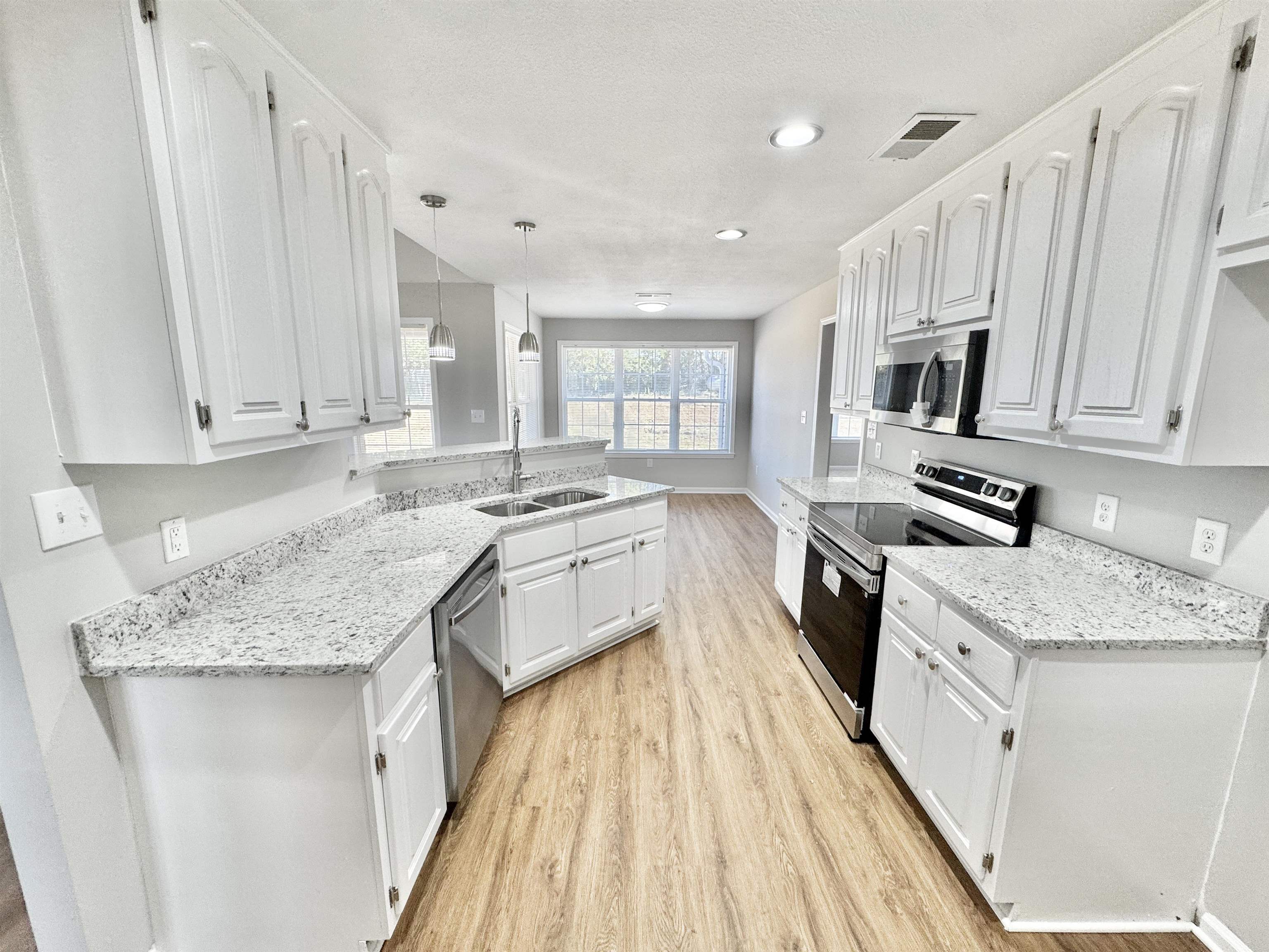 788 Bruce Road Whiteville, TN 38075 - Photo 6 of 39 Kitchen featuring appliances with stainless steel finishes, light stone counters, decorative light fixtures, a peninsula, and white cabinetry