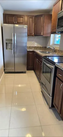 a kitchen with granite countertop a refrigerator and a stove top oven
