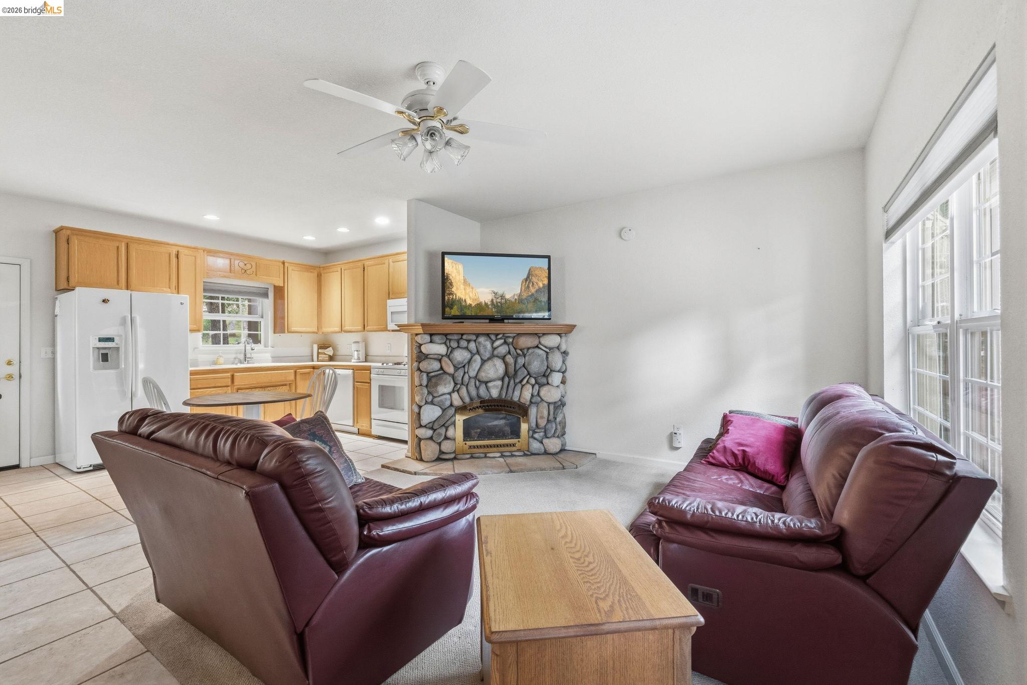 18450 Lambert Lake Road Sonora, CA 95370 - Photo 52 of 87 Living area featuring a stone-clad fireplace, a ceiling fan, and a large window