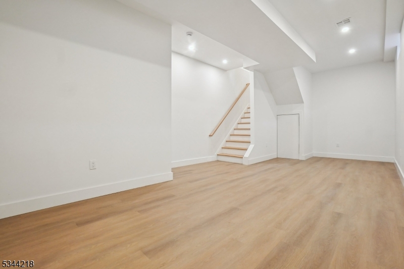51 New Street, Unit B Montclair, NJ 07042 - Photo 22 of 32 an empty room with wooden floor and staircase