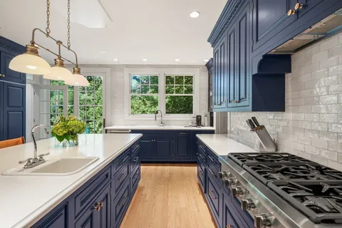 a kitchen with stainless steel appliances granite countertop a sink a stove and a wooden cabinets