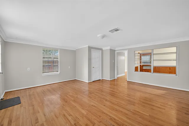 a view of an empty room with a window and wooden floor