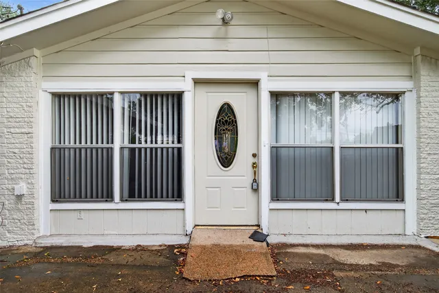 an empty room with wooden floor chandelier fan and windows