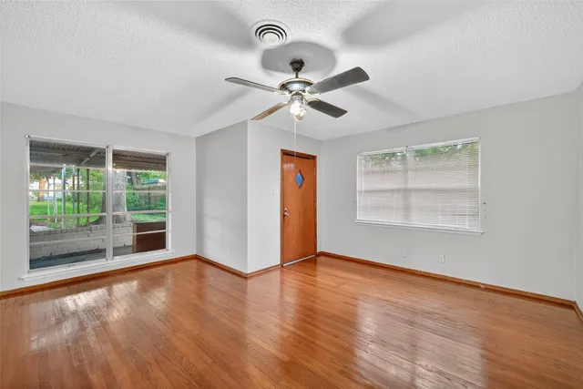 an empty room with wooden floor and window