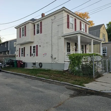 a view of a white house with large windows next to a road