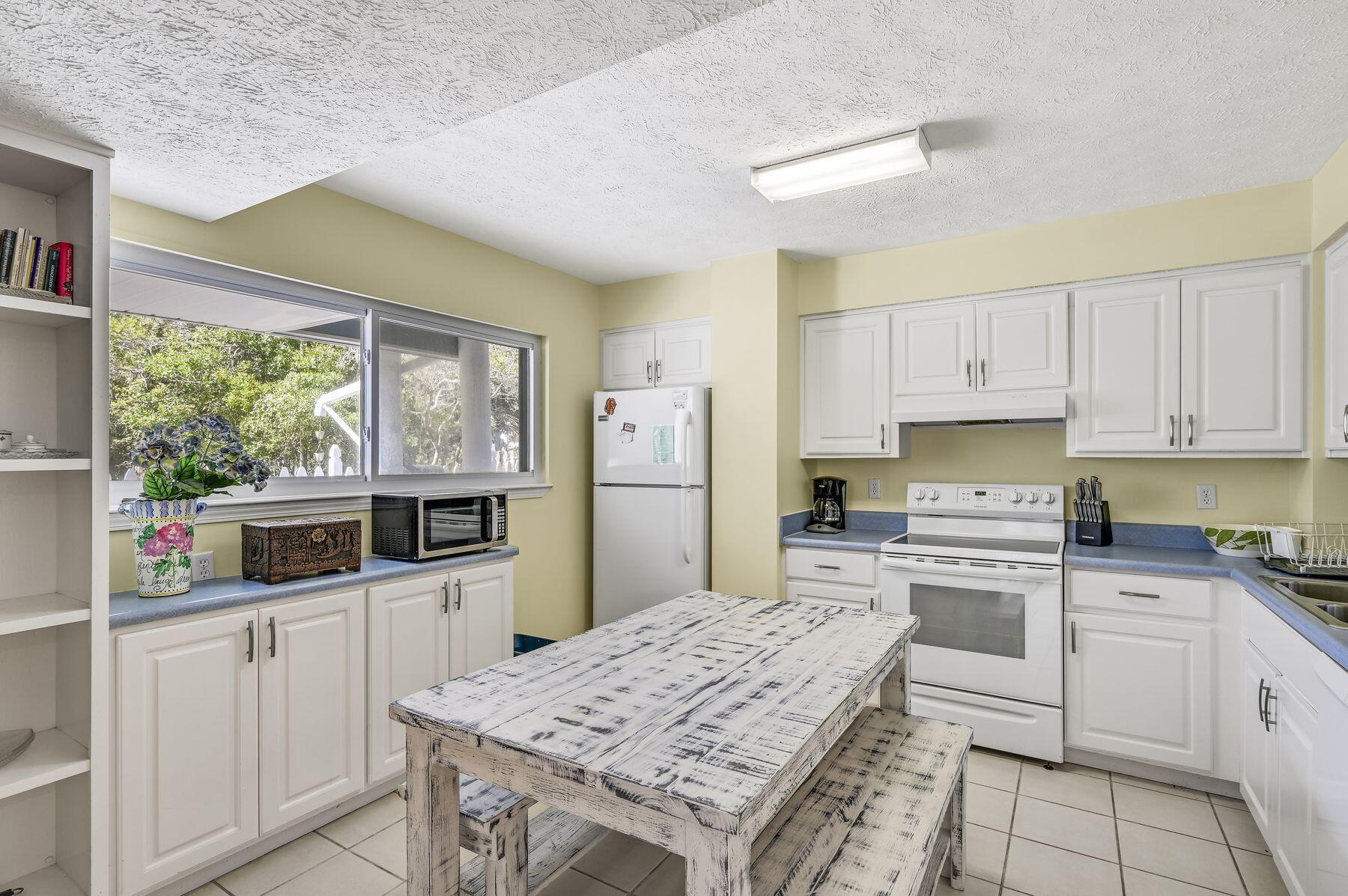 169 Pompano Street Inlet Beach, FL 32461 - Photo 40 of 49 a kitchen with stainless steel appliances granite countertop a stove top oven a sink a refrigerator white cabinets and dining table with wooden floor