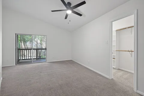 an empty room with windows and ceiling fan