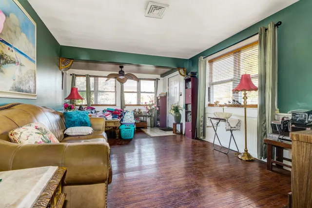 a living room with furniture large windows and wooden floor