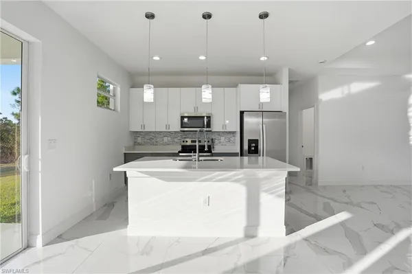 a view of a kitchen with kitchen island a counter top stainless steel appliances and cabinets