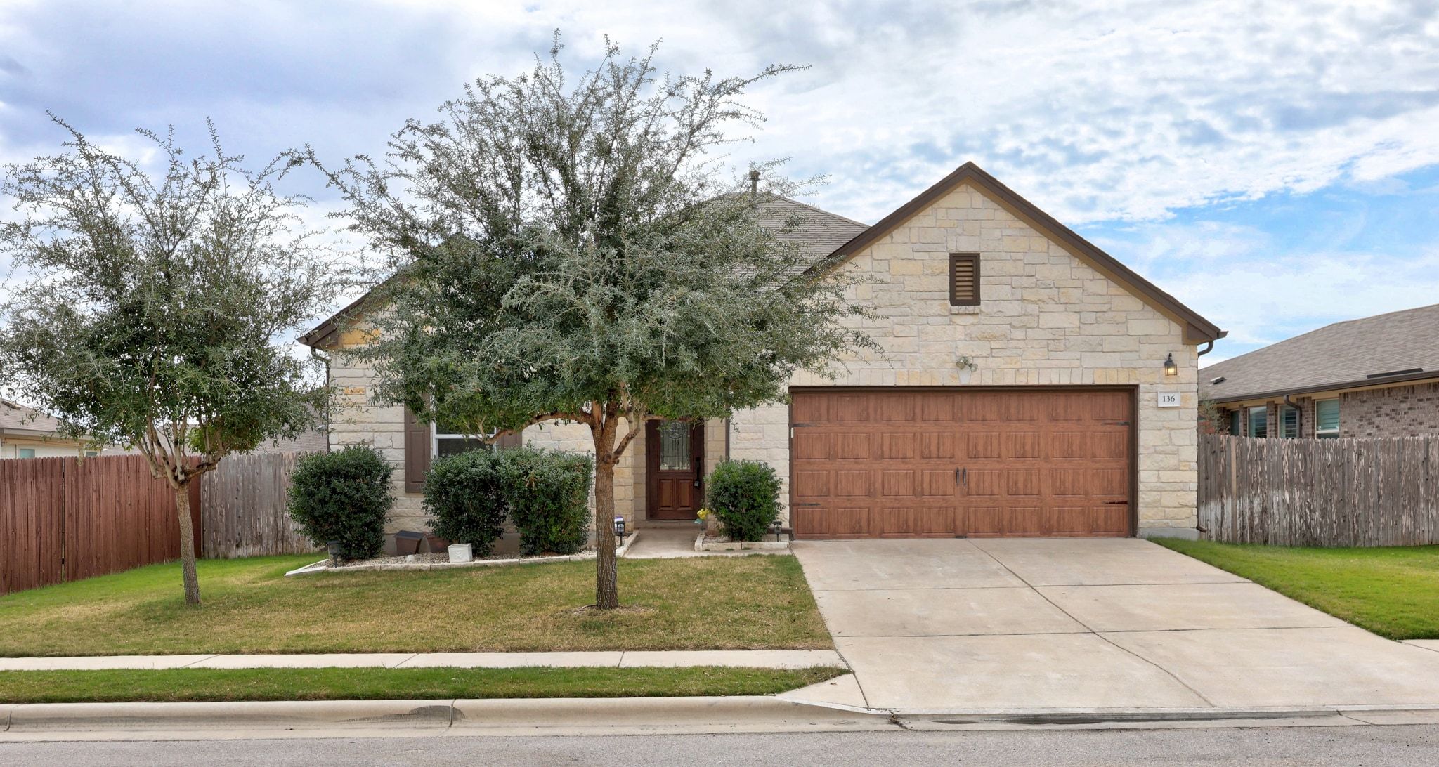View of front of property featuring stone siding, concrete driveway, and a garage