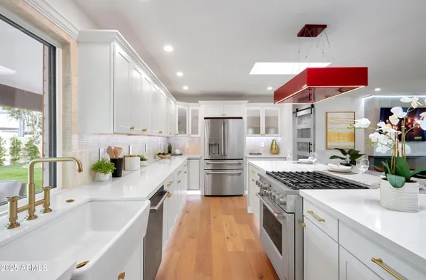 a kitchen with a stove a sink and a dining table with wooden floor
