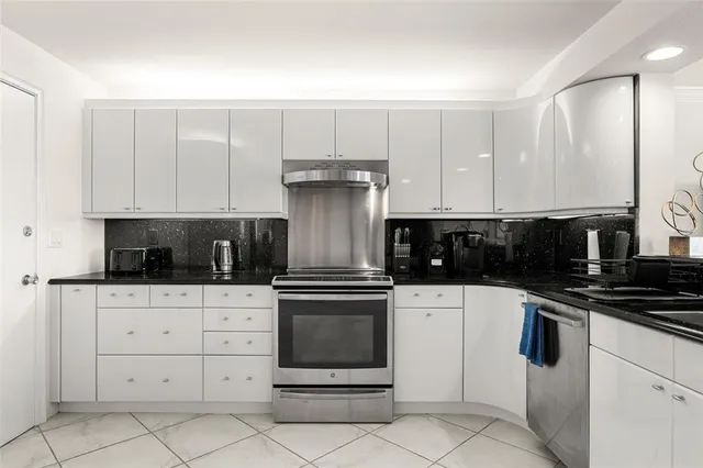 a kitchen with stainless steel appliances kitchen island granite countertop a refrigerator and a sink
