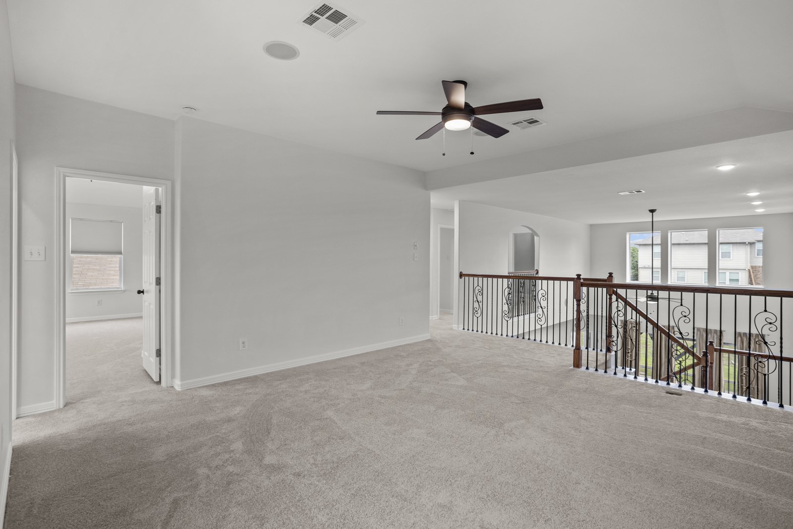 245 Razzmatazz Trail Buda, TX 78610 - Photo 24 of 37 Expansive carpeted loft with decorative iron balusters, a ceiling fan with integrated lighting, recessed lighting, and a visible speaker system