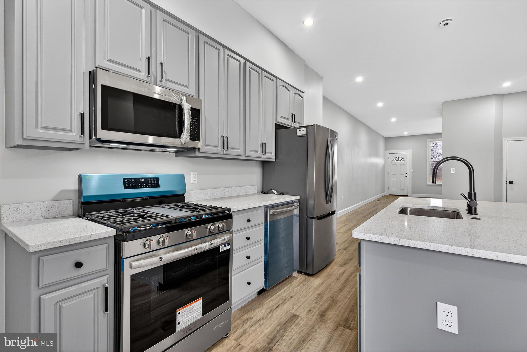 a kitchen with stainless steel appliances granite countertop a stove a sink and a microwave