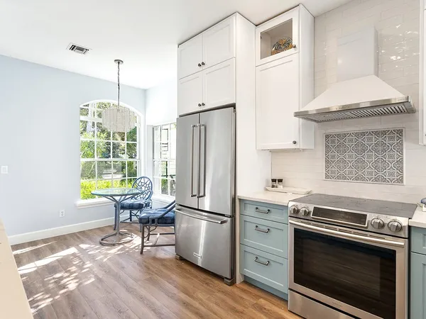 a kitchen with stainless steel appliances granite countertop a stove a refrigerator and a white cabinets