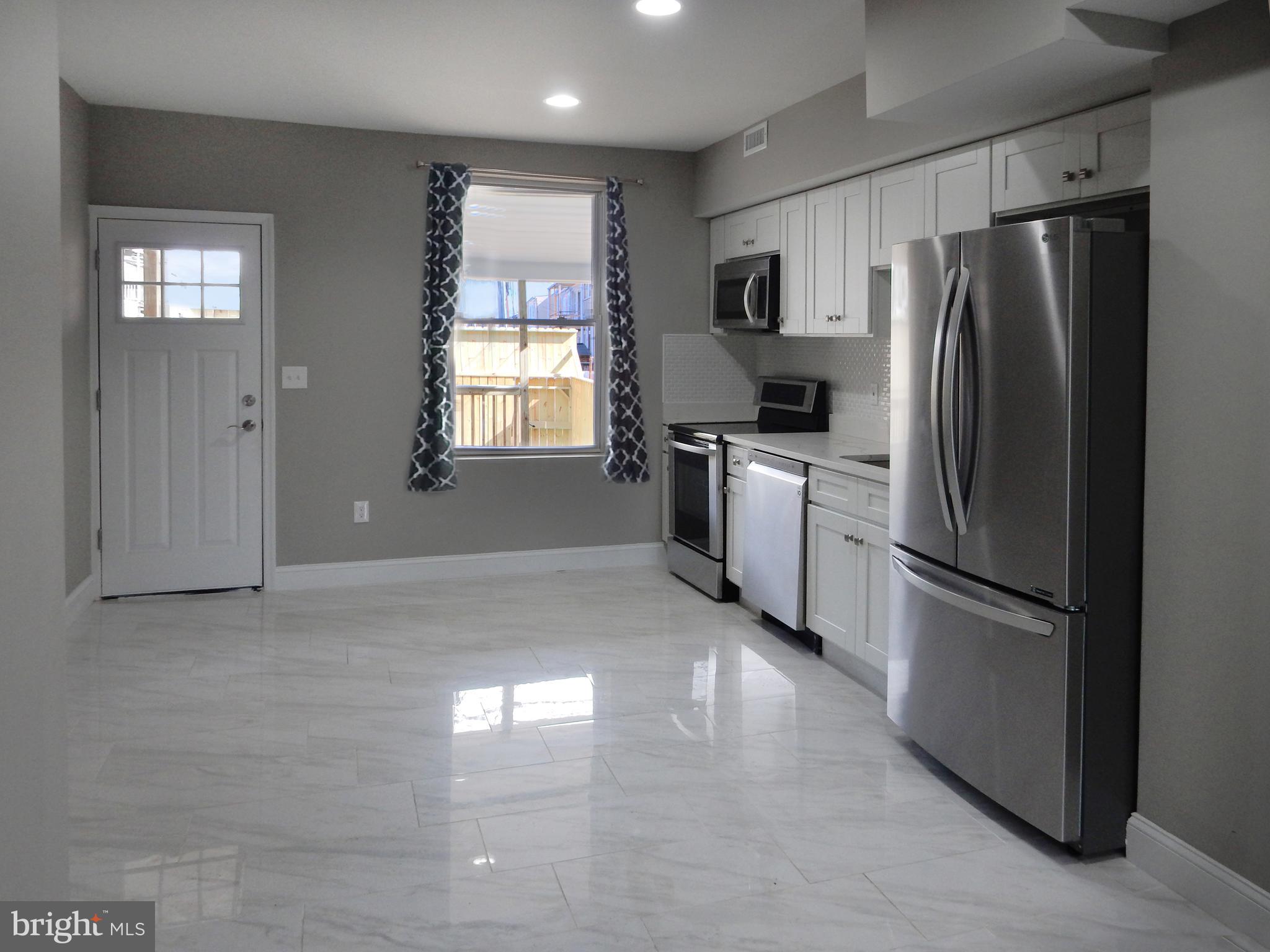 1111 Bayard Street Baltimore, MD 21223 - Photo 8 of 41 a kitchen with stainless steel appliances white cabinets and a refrigerator