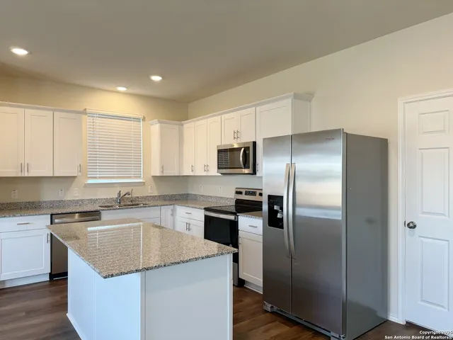 a kitchen with stainless steel appliances granite countertop a refrigerator a sink a stove a microwave and island