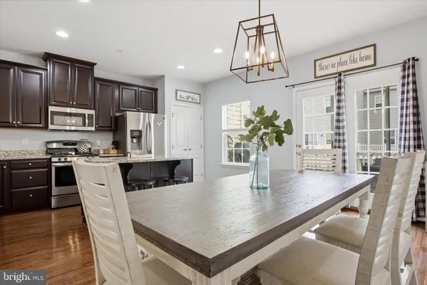 a kitchen with stainless steel appliances a dining table chairs refrigerator and microwave