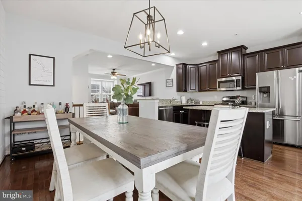a kitchen with stainless steel appliances a table chairs refrigerator and cabinets