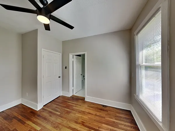 a view of an empty room with wooden floor and a window
