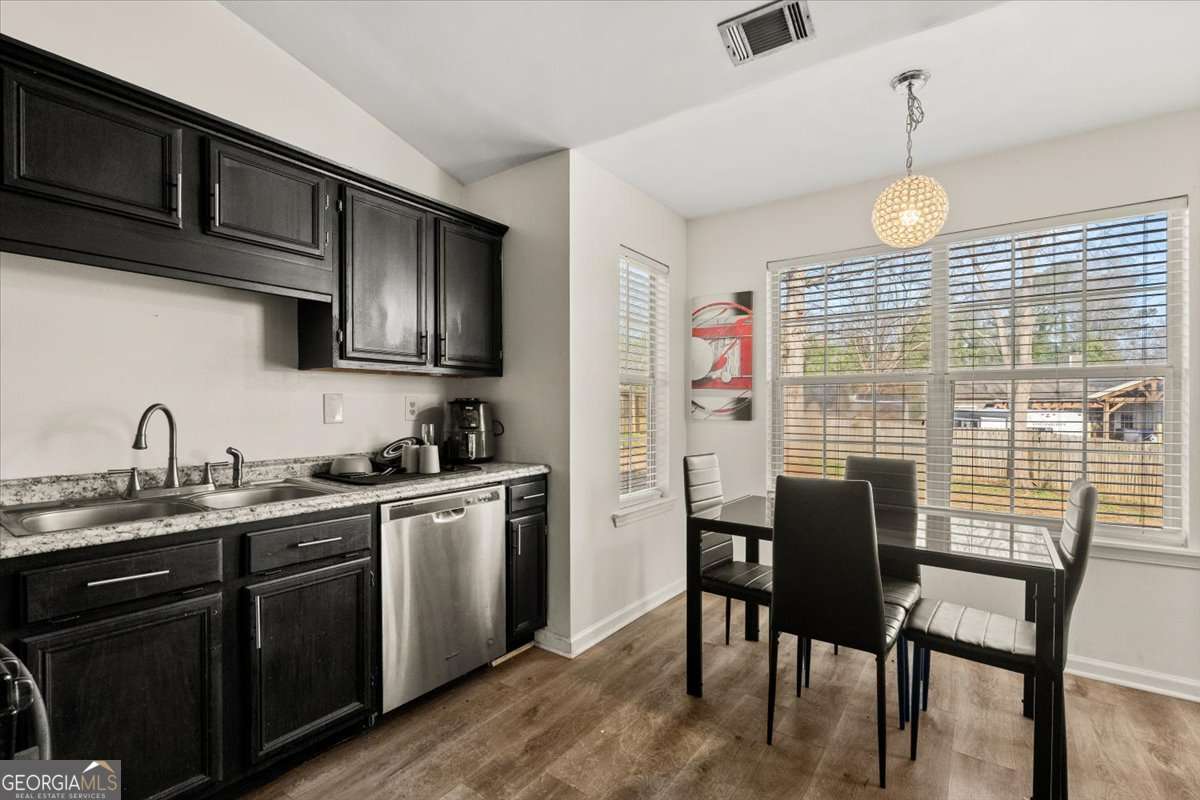 1362 Tara Road Jonesboro, GA 30238 - Photo 11 of 30 a kitchen with stainless steel appliances granite countertop a stove top oven a sink dishwasher a dining table and chairs with wooden floor