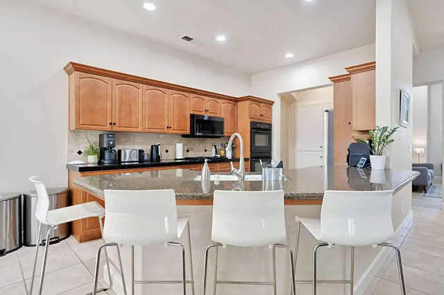a kitchen with stainless steel appliances a dining table chairs and a refrigerator