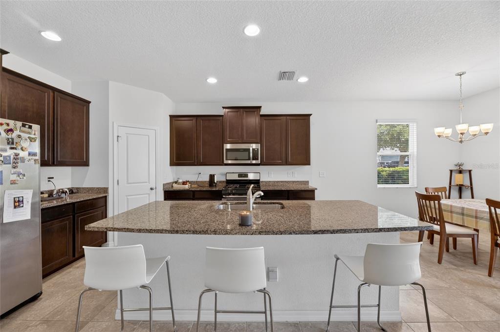 6309 Shadowlake Drive Apollo Beach, FL 33572 - Photo 12 of 64 a kitchen with stainless steel appliances granite countertop a stove a sink a microwave a dining table and chairs