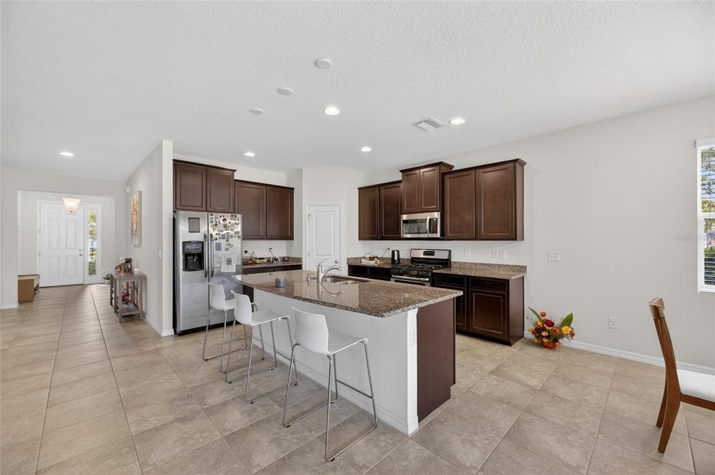 6309 Shadowlake Drive Apollo Beach, FL 33572 - Photo 5 of 64 a kitchen with stainless steel appliances a stove top oven a sink dishwasher a refrigerator and white cabinets with wooden floor