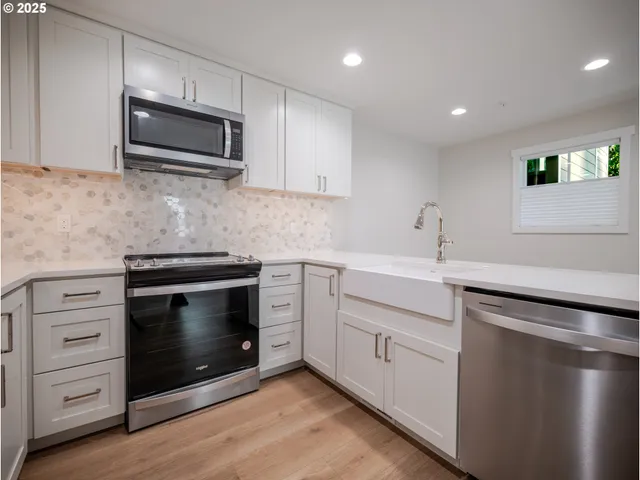 a kitchen with white cabinets stainless steel appliances and wooden floor