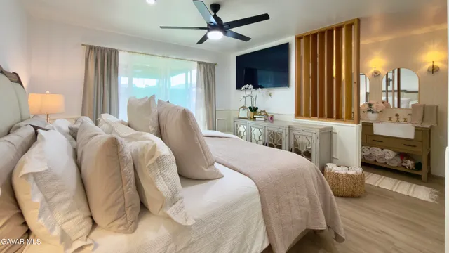 a bedroom with a bed a flat screen tv and a large window