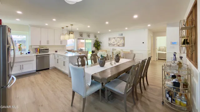 a dining room with stainless steel appliances kitchen island granite countertop a table chairs and a refrigerator