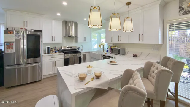 a kitchen with stainless steel appliances granite countertop a sink a stove a refrigerator cabinets and chairs