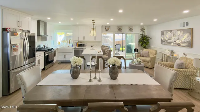 a kitchen with stainless steel appliances granite countertop a refrigerator a stove and white cabinets with wooden floor