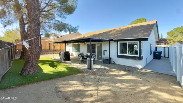 a view of a patio with table and chairs under an umbrella with large trees