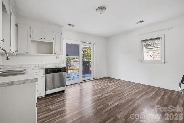 a kitchen with stainless steel appliances granite countertop a stove top oven a sink dishwasher and a refrigerator with wooden floor