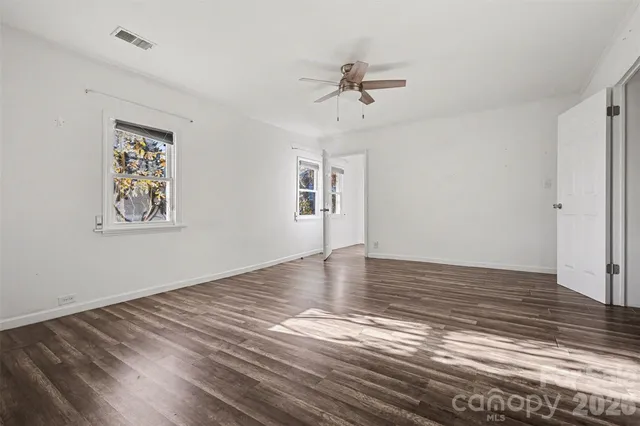 a view of empty room with wooden floor and fan