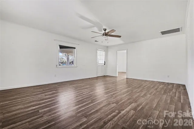 a view of an empty room with a window and wooden floor