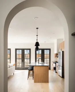 a kitchen with stainless steel appliances a refrigerator a sink a stove and a dining table with wooden floor