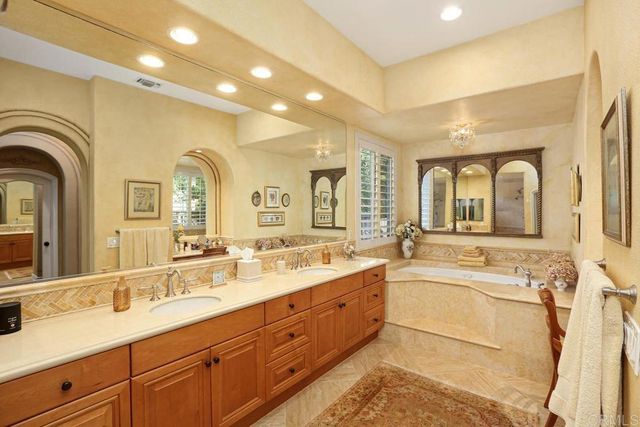 a large bathroom with a granite countertop sink a mirror and a with bathtub