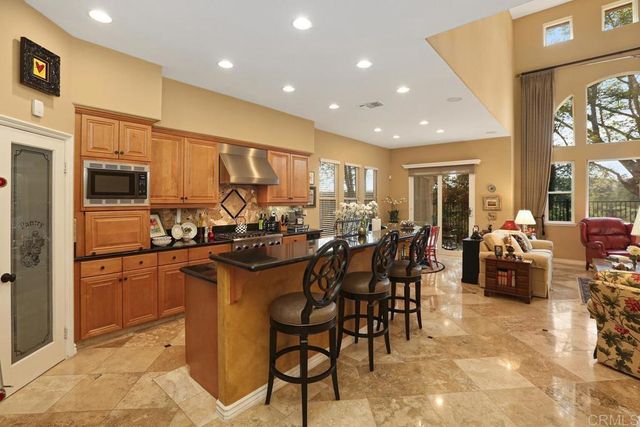a kitchen with stainless steel appliances a sink a stove a refrigerator cabinets and a dining table with wooden floor