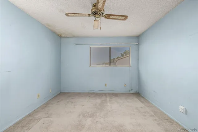 an empty room with a ceiling fan and windows