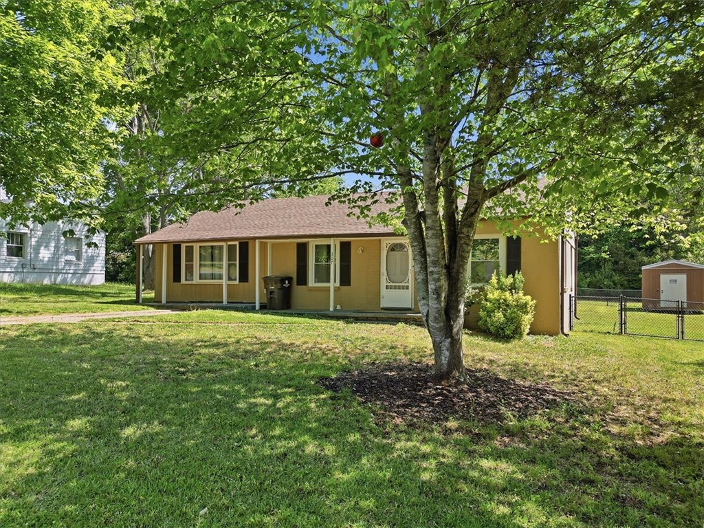 307 South Elm Street Pendleton, SC 29670 - Photo 5 of 41 A charming single-story residence with a welcoming front porch is nestled amidst lush greenery.