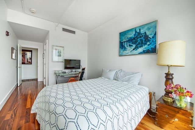 a bedroom with a bed and a lamp on dresser