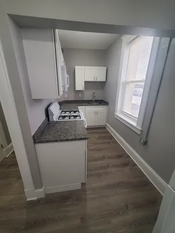 a kitchen with granite countertop a sink stove and cabinets