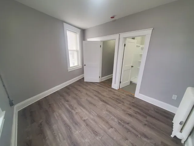 a view of an empty room with wooden floor and window