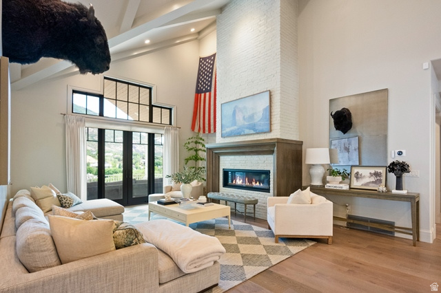 3 Carriagewood Cove, Unit 1088 Sandy, UT 84092 - Photo 16 of 79 Spacious living area featuring a vaulted ceiling with exposed beams, light wood-finish flooring, and a floor-to-ceiling brick fireplace with a wood mantel