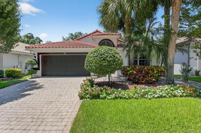 a front view of a house with a garden and a tree